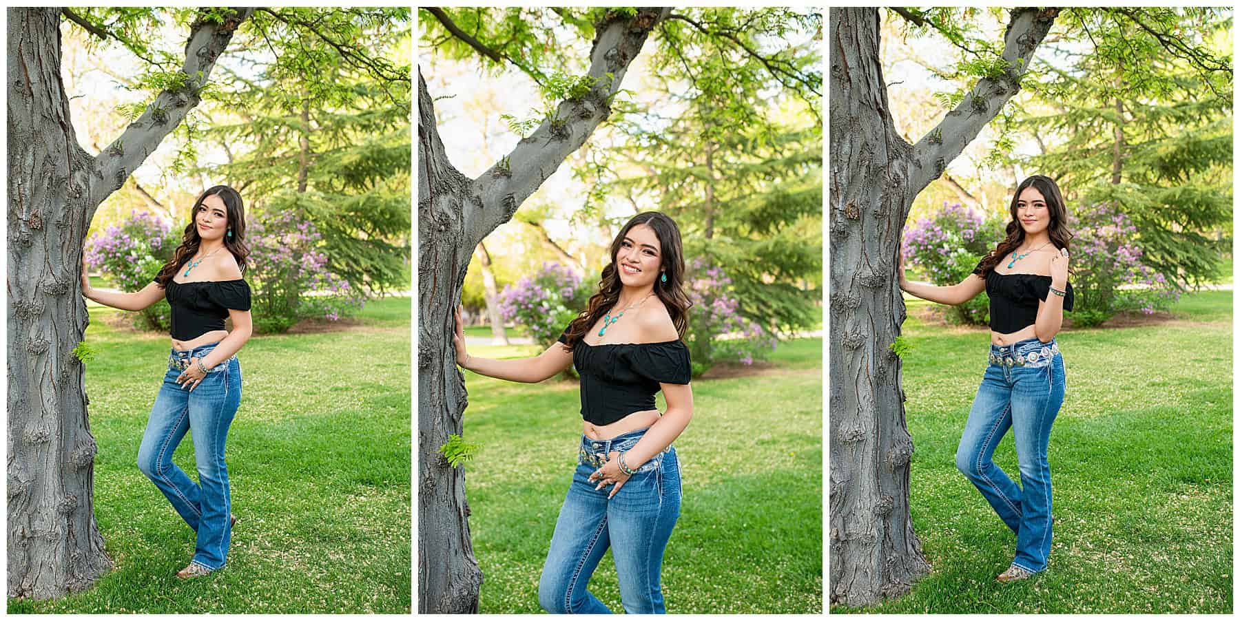 Senior girl in a black top, jeans, and boots posing in front of lilac bushes showing her country-inspired style.